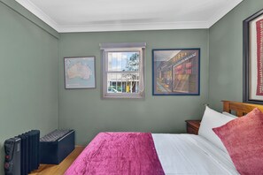 Ein Schlafzimmer mit einem Bett, einem Fenster, einer Karte und einem gerahmten Bild.