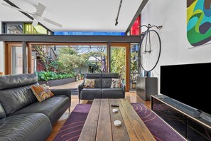 Ein modernes Wohnzimmer mit einem Ledersofa, einem Holztisch und einem großen Flachbildfernseher.