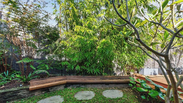 A garden with a stone bench, a small pond, and various plants. - Kingsley Discover Cafs Street Art and Village Life (Newtown)
