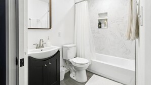 Een badkamer met een wit wastafelmeubel, toilet en bad.