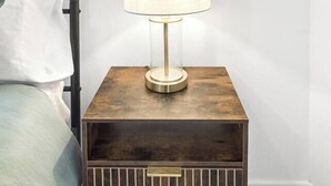 A bedside table with a lamp, a bed with a pillow, and a wooden floor.
