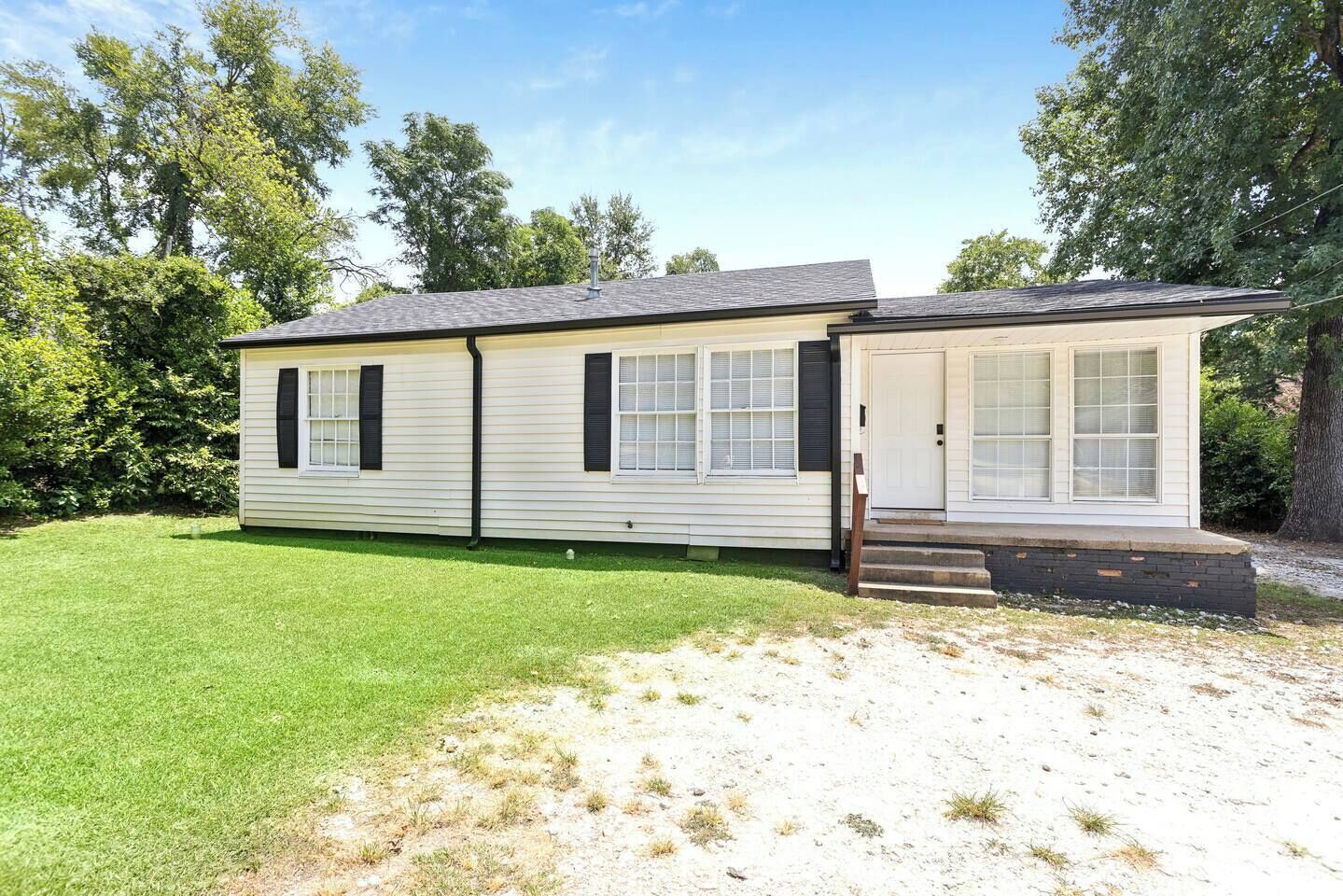 Une maison mobile de plain-pied, dotée d’un porche à l’avant, d’un petit garage attenant et d’une pelouse bien entretenue.