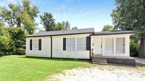 A single-story mobile home with a front porch, a small attached garage, and a well-maintained lawn.