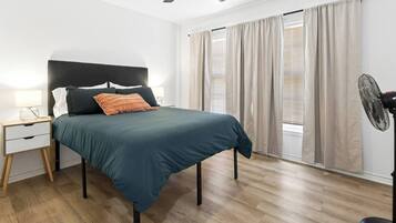 Ein Schlafzimmer mit Bett, Nachttisch, Lampe und Deckenventilator.