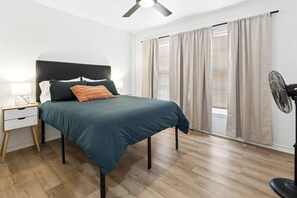 A bedroom with a bed, nightstand, lamp, and a ceiling fan.