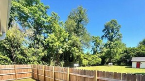 A fenced backyard with a wooden deck and a small shed.