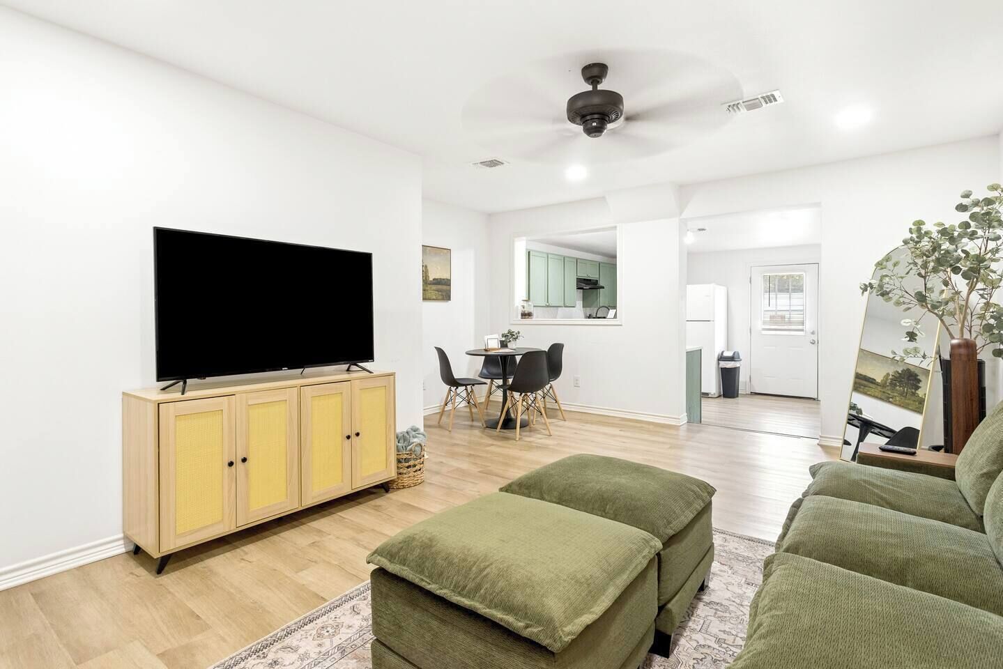 Un soggiorno moderno con una televisione a schermo piatto, un'area pranzo con sedie e una cucina sullo sfondo.