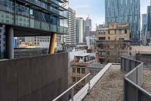 Eine Dachterrasse mit Blick auf eine Stadtlandschaft, darunter moderne Gebäude und ein historisches Bauwerk.