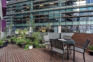 Une terrasse sur le toit avec une plateforme en bois, des sièges d’extérieur et des plantes en pot.