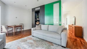 A modern living room with a grey sofa, wooden dining table, and chairs. - Skyline Terrace Central CBD Escape with City Views (Melbourne)