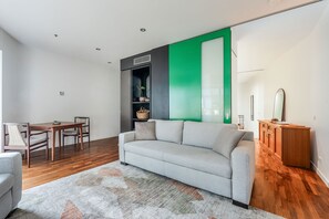 A modern living room with a grey sofa, wooden dining table, and chairs. - Skyline Terrace Central CBD Escape with City Views (Melbourne)