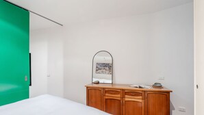 A bedroom with a bed, a wooden dresser, a mirror, and a green door. - Skyline Terrace Central CBD Escape with City Views (Melbourne)