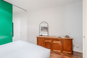 A bedroom with a bed, a wooden dresser, a mirror, and a green door. - Skyline Terrace Central CBD Escape with City Views (Melbourne)