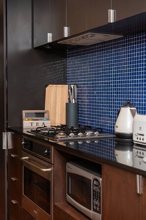 A kitchen with a gas stove, a microwave, and a toaster on the counter. - Skyline Terrace Central CBD Escape with City Views (Melbourne)