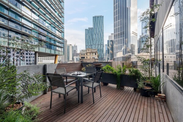Une terrasse sur le toit, aménagée avec des espaces de détente en plein air, des plantes en pot et offrant une vue panoramique sur la ville.