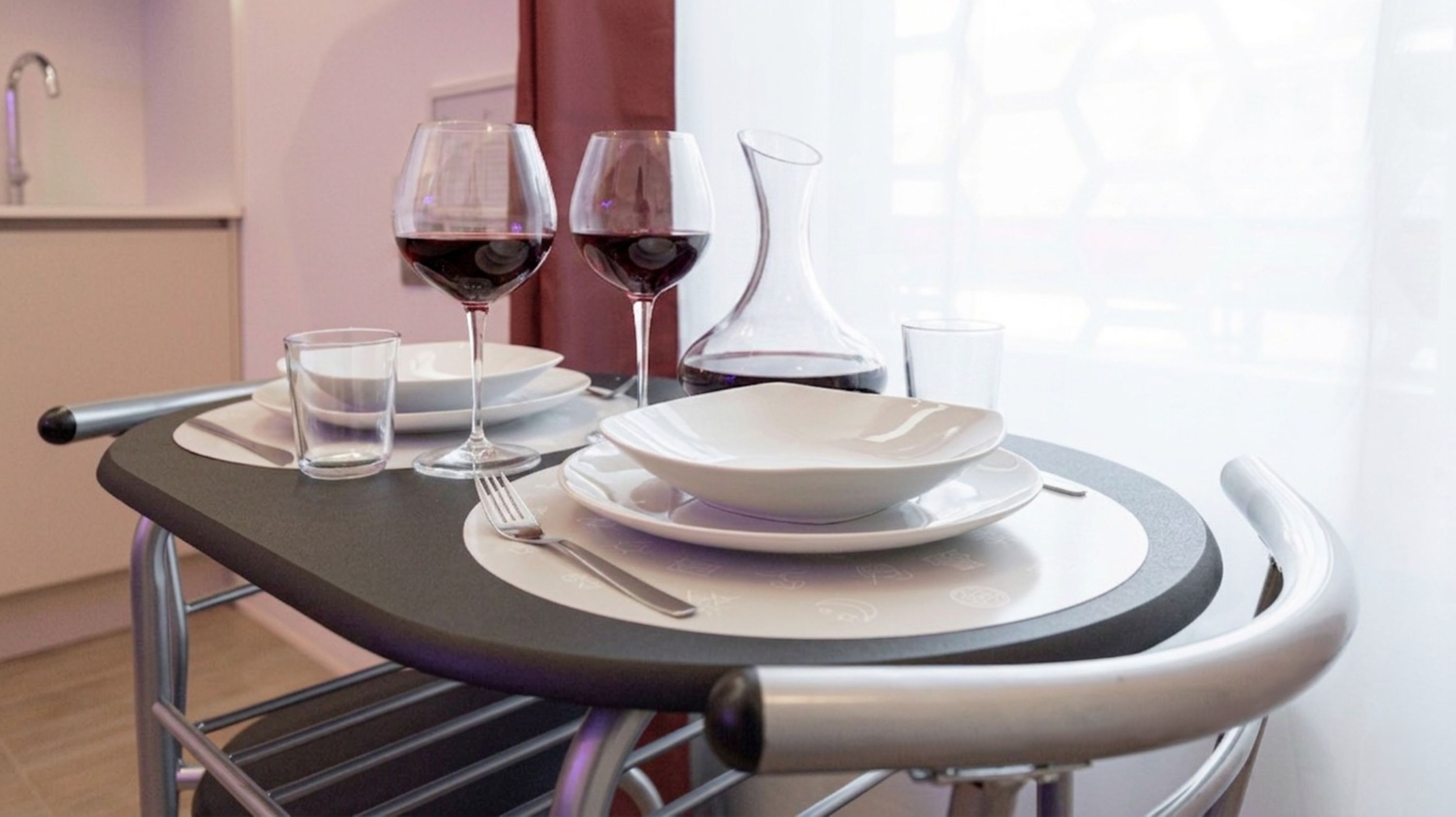 A table with a wine glass, a water glass, and a white bowl set on a tray.