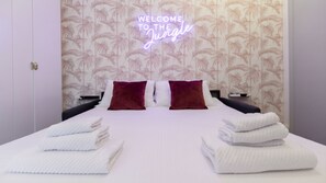 A hotel room with a bed, two pillows, a neon sign, and a tropical wallpaper. - Italianway Collection - Corso Venezia 7 - Boheme (Milan)