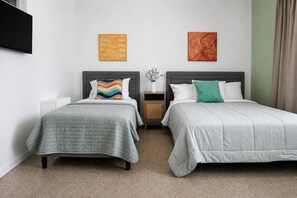 A hotel room with two beds, a nightstand, a vase with flowers, and two wall art pieces. - 1BR Near Escambrón Beach & Old San Juan (San Juan)