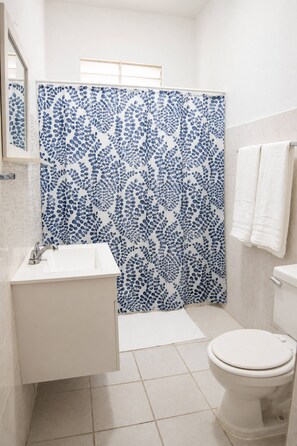 A bathroom with a shower curtain, sink, and toilet. - 1BR Near Escambrón Beach & Old San Juan (San Juan)