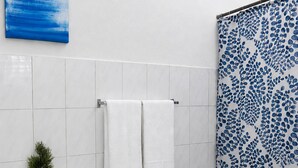 Ein Badezimmer mit Toilette, Waschbecken, einer Dusche mit blau gemustertem Vorhang und einem kleinen Blumentopf.