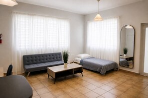A modern, well-lit bedroom with a grey sofa, a single bed, a bedside table, and a large mirror. - Spacious Budget-Friendly 1BR by Escambron Beach (San Juan)