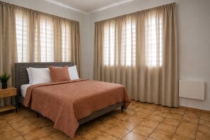 A bedroom with a bed, curtains, a nightstand, and a radiator. - Spacious Budget-Friendly 1BR by Escambron Beach (San Juan)