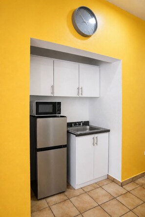 A compact kitchen with a microwave, stove, and cabinets against a yellow wall. - Spacious Budget-Friendly 1BR by Escambron Beach (San Juan)