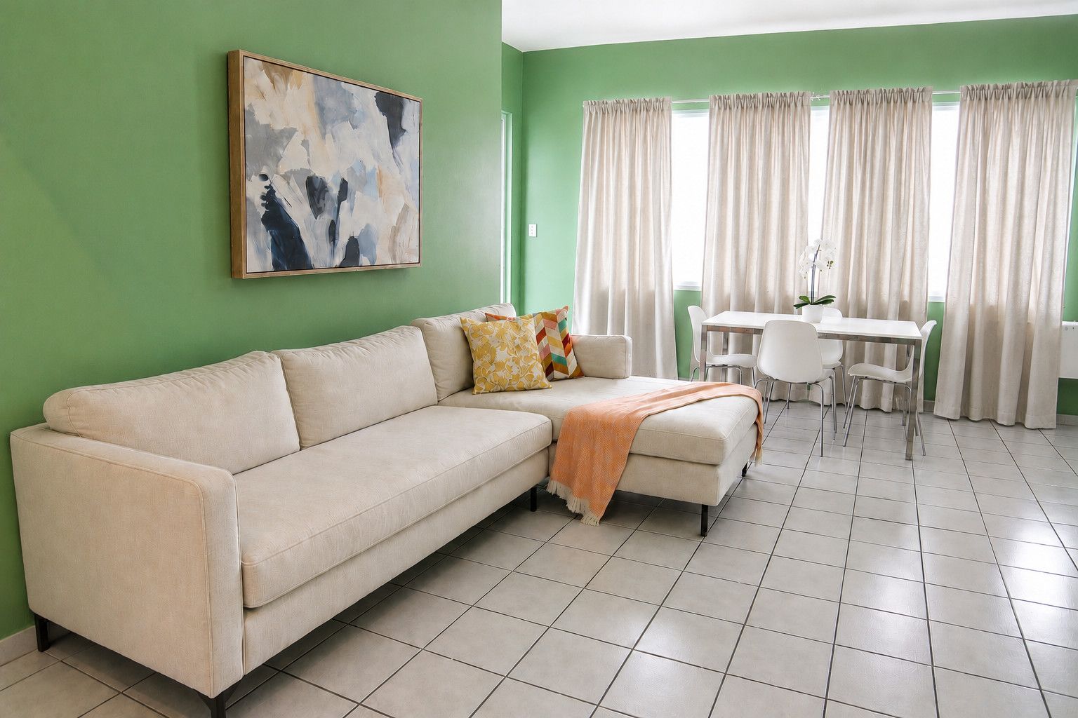 Ein Wohnzimmer mit einer Couch, einem Couchtisch und einem Essbereich mit Stühlen und Vorhängen.