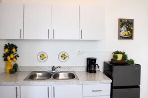 A kitchen with white cabinets, a double sink, a coffee maker, and a refrigerator. - Vibrant 1BR w Balcony, Steps to Escambron Beach (San Juan)