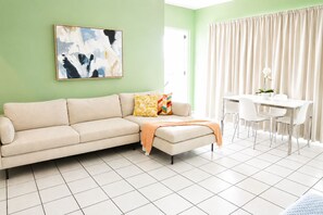 Ein Wohnzimmer mit einer Couch, einem Couchtisch und einem Essbereich mit Stühlen und Tisch.
