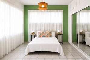 A bedroom with a bed, two bedside tables with lamps, a large mirror, and sheer curtains. - Vibrant 1BR w Balcony, Steps to Escambron Beach (San Juan)