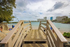 A wooden boardwalk leading to a beach with a view of a city skyline and palm trees. - Vibrant 1BR w Balcony, Steps to Escambron Beach (San Juan)