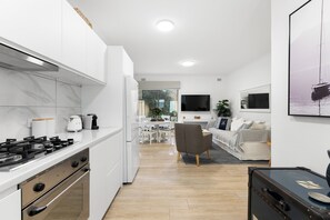 Une cuisine moderne avec des meubles blancs, une cuisinière et un coin repas comprenant une table et des chaises.