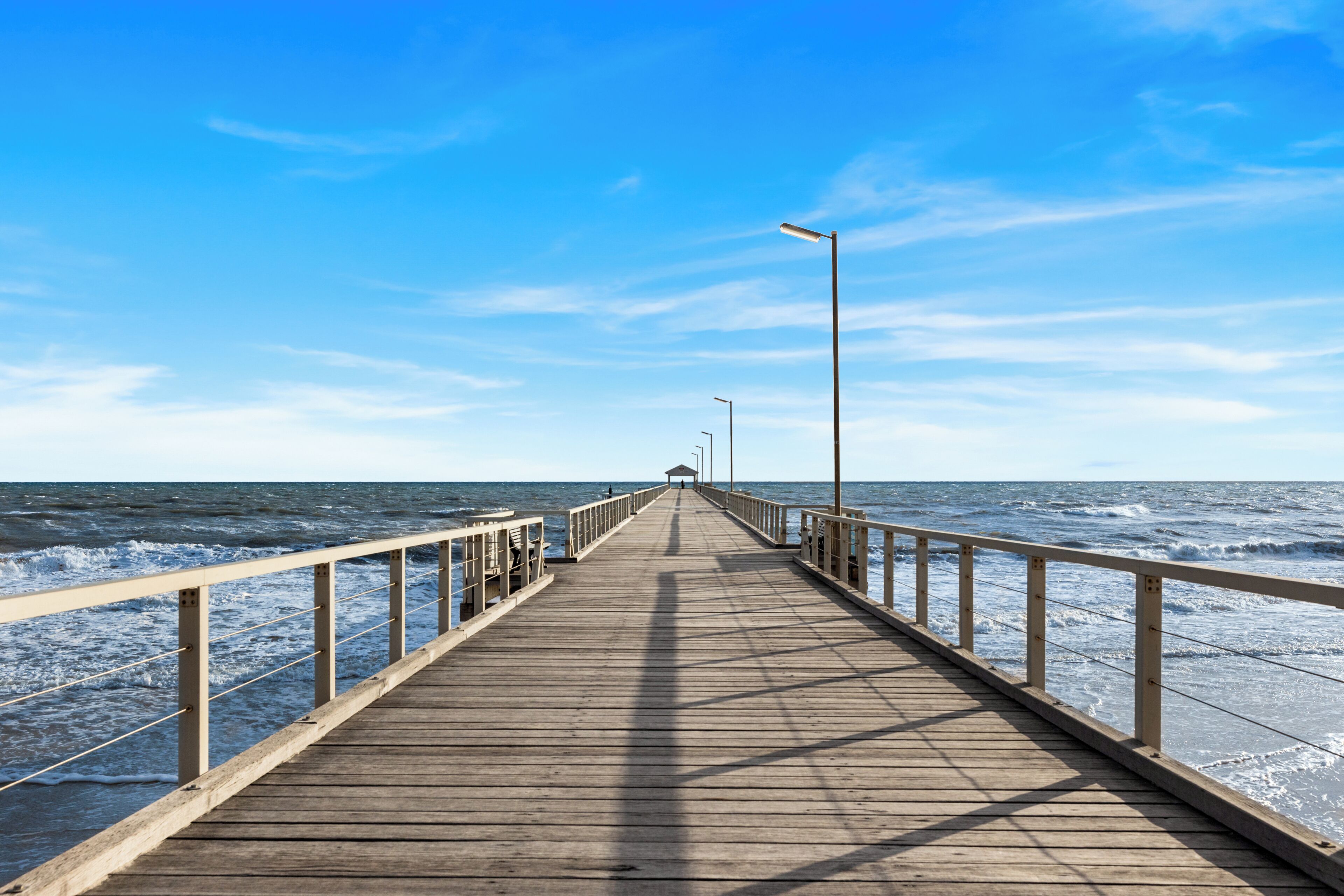 A wooden pier extending into the sea with railings on both sides.