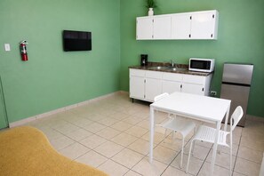 A compact kitchen with a white table, chairs, a microwave, a refrigerator, a sink, and cabinets. - Charming 1 BR Walking Distance to Escambron Beach (San Juan)