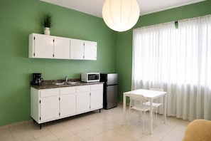 A kitchen with white cabinets, a microwave, a refrigerator, a coffee maker, and a dining table with chairs. - Charming 1 BR Walking Distance to Escambron Beach (San Juan)