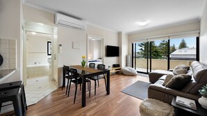 Ein modernes Wohnzimmer mit Essbereich, einer Couch, einem Fernseher und einem Balkon mit Blick.