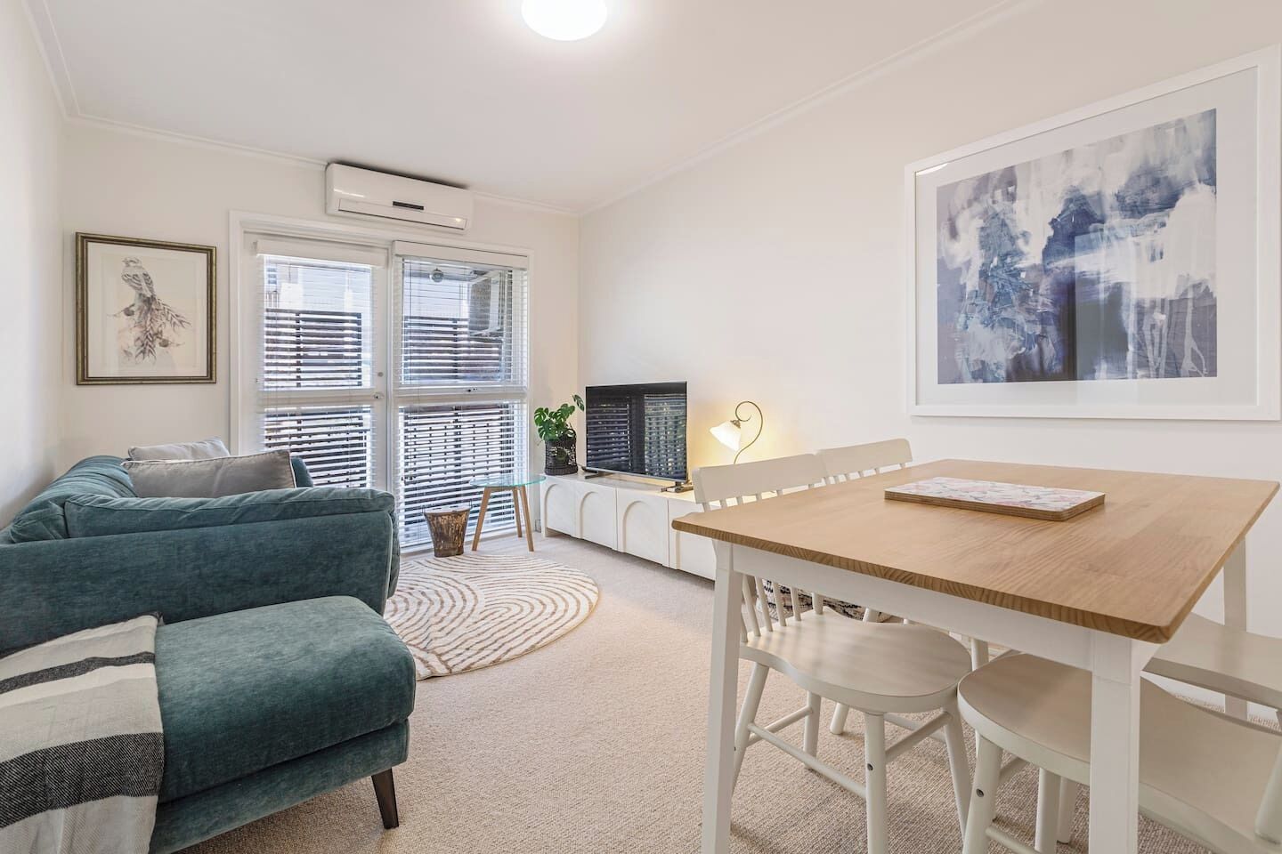 A modern living room with a sofa, a dining table, and a TV.