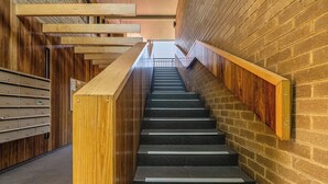 Eine Treppe mit Holheitslaufgeländern und einer Ziegelwand.