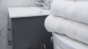 A bathroom with a marble wall, a sink, a mirror, and a towel rack. - Bright & Comfortable 2BR San Juan Getaway (San Juan)