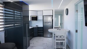 A modern kitchen with a built-in microwave, a stainless steel refrigerator, and a white dining table with chairs. - Bright & Comfortable 2BR San Juan Getaway (San Juan)