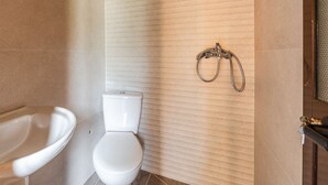 A bathroom with a toilet, a sink, and a shower area.