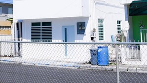 A white multi-story building with a flat roof, multiple windows, and a visible balcony. - Stunning & Cozy 2-Bedroom San Juan Apartment (San Juan)