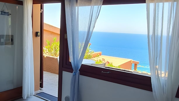 Una stanza con vista sul mare, un lampadario a soffitto e una porta che dà sull'esterno.