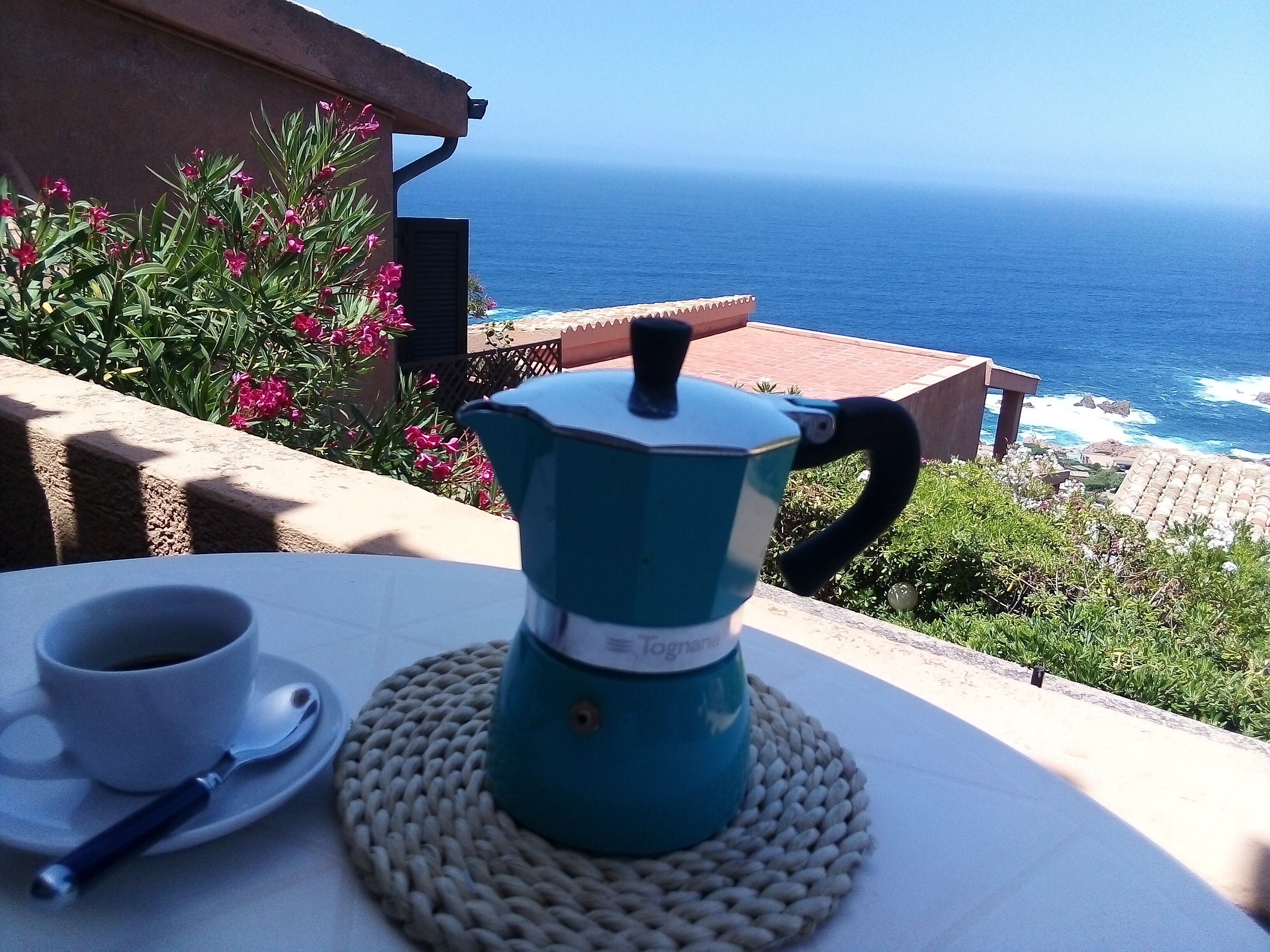 Ein Tisch mit Kaffeekanne und Tasse, mit Blick auf die Küste.