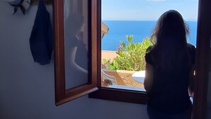 Una stanza con una grande finestra, un letto e vista sul mare.