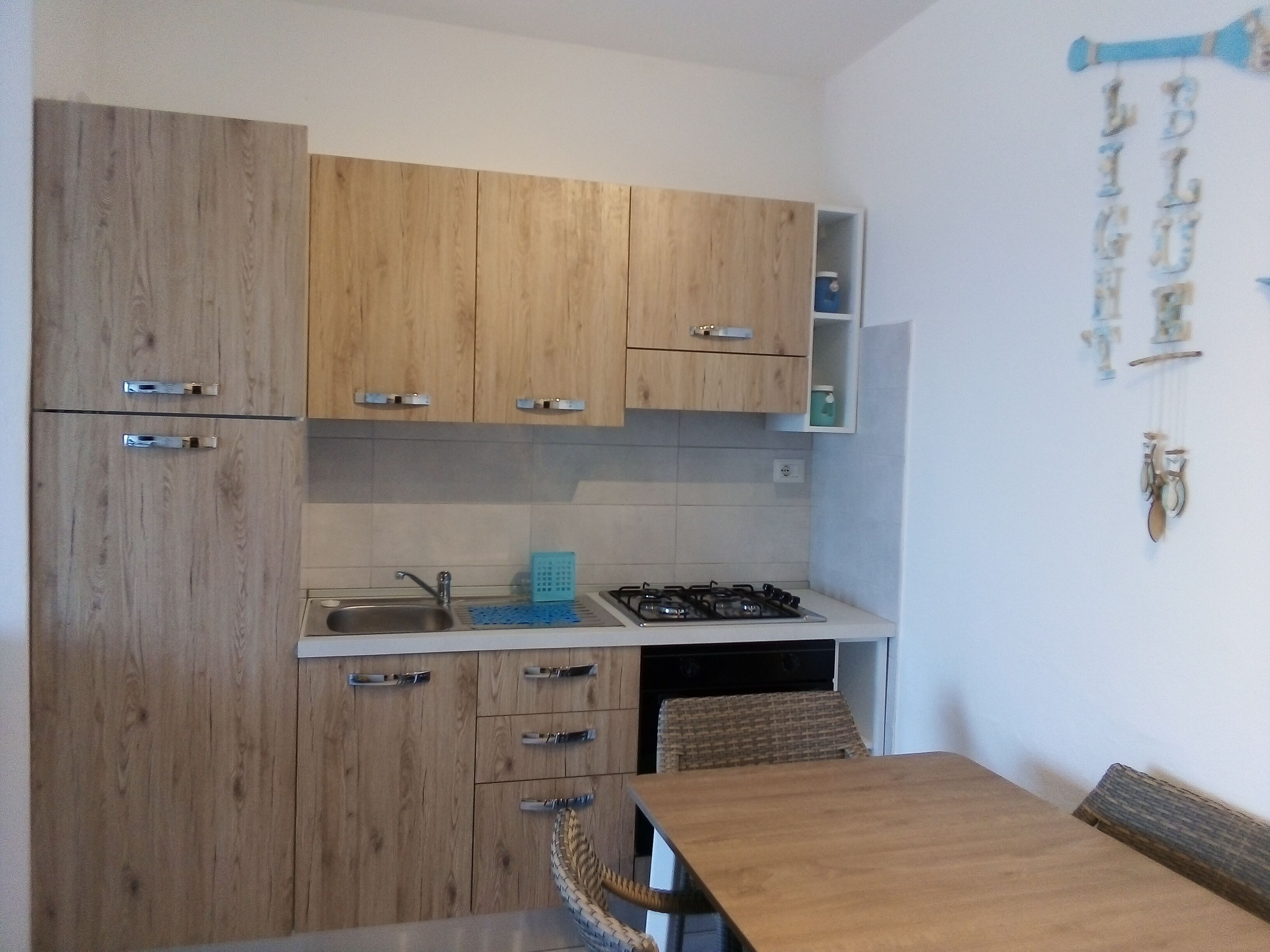 Cocina con armarios de madera, estufa a gas y lavabo.