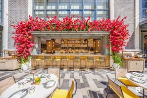 An outdoor bar area with a bar counter, seating, and a view of the building behind. - Downtown Studio Near Kaseya - Pool & Gym (Miami)