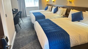 A hotel room with two beds, a desk, and a chair.