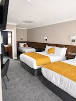 Habitación de hotel con dos camas, un escritorio, una silla y un baño.